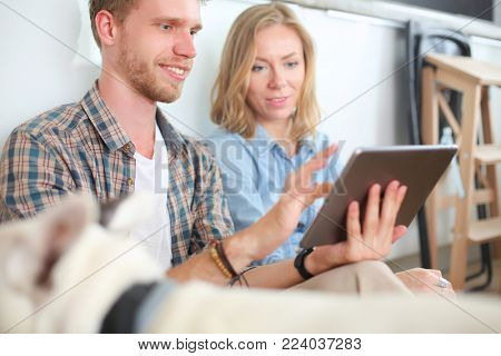 Young couple moving in new home.Sitting and relaxing after unpacking.Looking something on laptop. Young couple