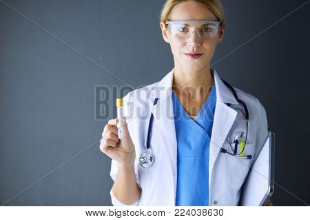 Female medical or research scientist or doctor using looking at a test tube of clear solution in a lab or laboratory.