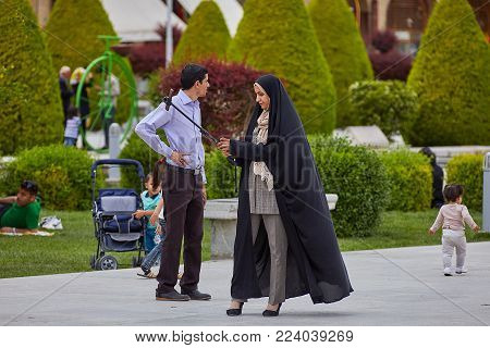 Isfahan, Iran - April 24, 2017: The Iranian family photographs themselves in the Naghsh-e Jahan Square, using a selfie-stick and a smartphone.