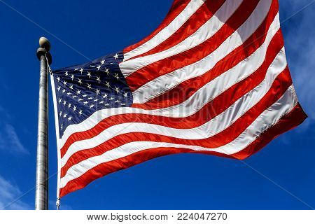 USA. Wind blown flag of the United States of America over sky background.
