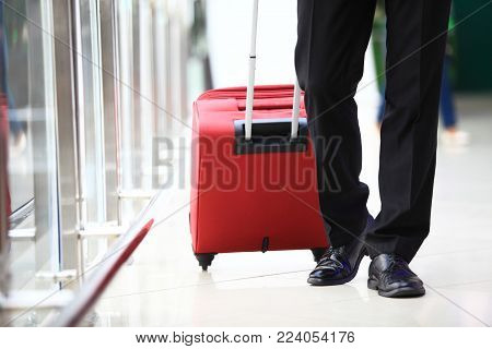 Business trip. Close-up of businessman carrying suitcase while walking through a passenger boarding bridge