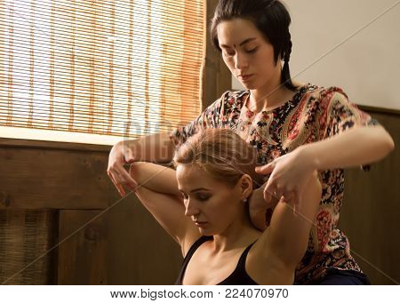 Masseur massaging back of female in spa resort, relaxed patient enjoys. Thai massage or Thai yoga massage treatment