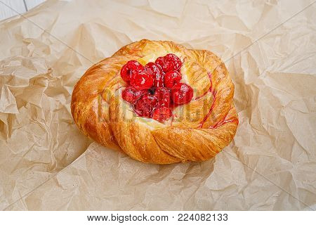 Puff with raspberries, lies on the basis of kraft paper.