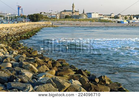 Lighthouse Warnemünde on the Baltic Sea in Germany Europe with stones in the foreground and shoreline with beach