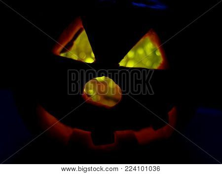Glowing pumpkin at Haloween symbolizing the head of a ghost on night spooky dark background. Soft focus. shallow DOF