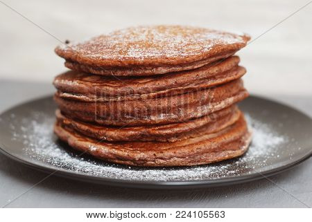 Holliday Breakfast. Chocolate Pancakes in Black Plate. Sugar Powder.