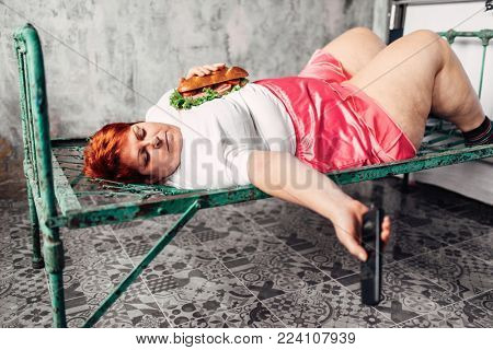 Fatty woman with sandwich in hands watches TV