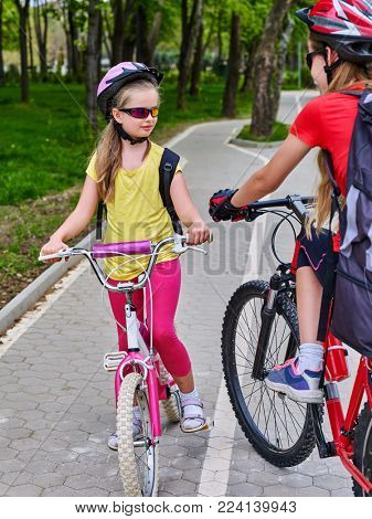 Bikes bicyclist girl. Girls wearing bicycle helmet and glass with rucksack ciclyng bicycle. Walking in spring is good for your health. Bike share program save money and time at city street.