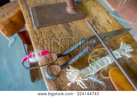 Close up of assorted materials, whool and scissors to work on loom manufacturing wool shawl clothing in Nepal.