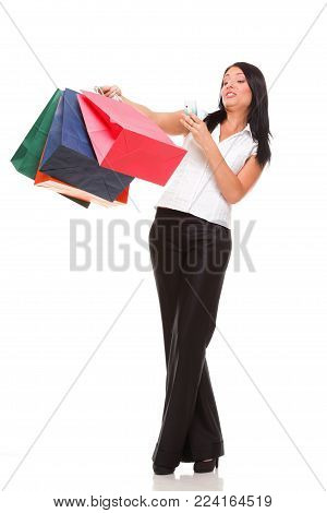 portrait of a cute young woman speaking on the mobile while holding shopping bags against white background