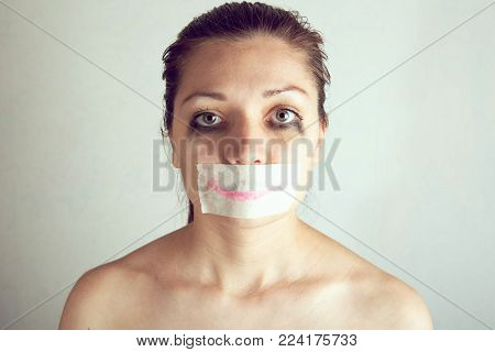 Unhappy woman with wrapping her mouth by adhesive tape painted smile.