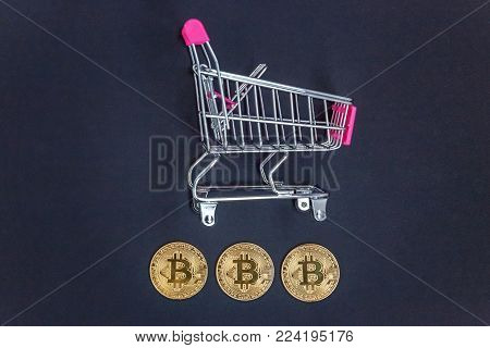 Stack of coins bitcoin in mini shopping cart toy, concept of mining. Electronic virtual money for web banking and international network payment. Symbol of crypto currency