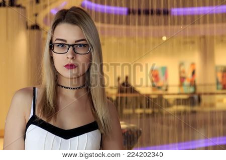 Beautiful blonde with glasses on a light background.