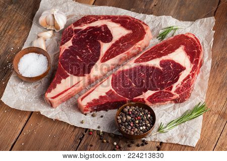 Two fresh raw marble meat, black Angus ribeye steak with spices on a old rustic table. Raw beef on a wooden background. Top view with copy space.