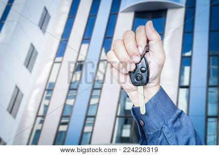 Hand Holding Car Key On Building Background
