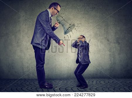 Angry business man boss screaming at himself small in megaphone