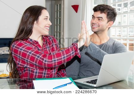Young couple receiving good newsat desk at modern home