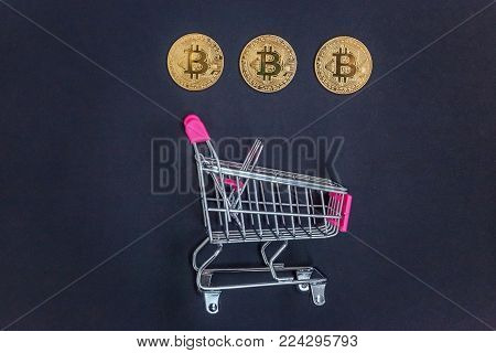 Stack of coins bitcoin in mini shopping cart toy, concept of mining. Electronic virtual money for web banking and international network payment. Symbol of crypto currency