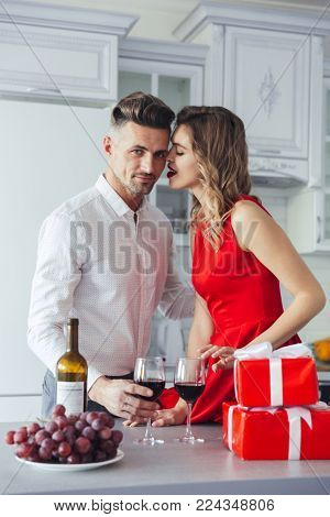Portrait of a young romantic smart dressed couple drinking wine while celebrating Valentine's Day on a kitchen at home