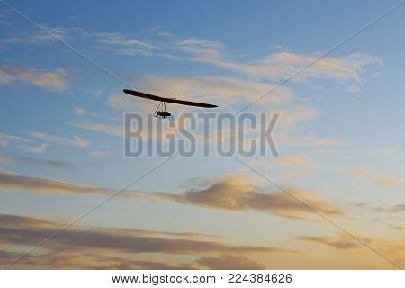 A lone hang glider silhouetted against a sunset sky.