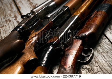 Different types of ancient hunting shotguns on wooden background. Collection of hunting rifles, close-up