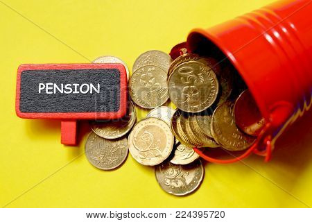 Top view of red pile with coins and blackboard written with 'PENSION' on yellow background. Business and finance theme.