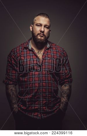 Brutal man in red t shirt and tattoo over grey wall.