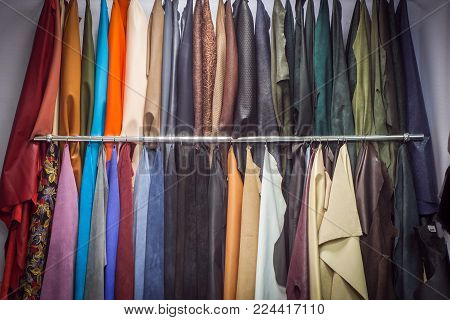 Pieces of natural and artificial skin of leather hang in several rows of different colors: brown, blue, green, red, black, white, beige, purple and other