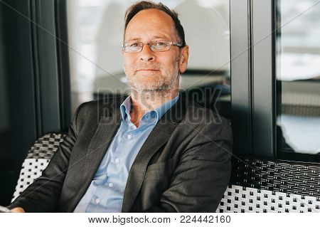 Outdoor portrait of 50 year old man wearing blue shirt, formal suit and eyeglasses