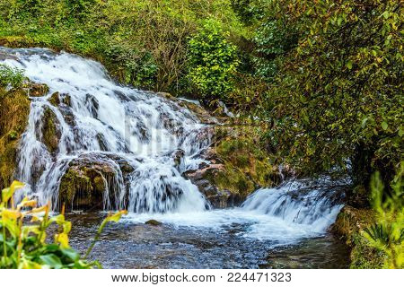 The concept of ecological and photo tourism. Slunj, Croatia. Little tourist town on the river Korana. Cascade waterfalls are lit by sunset rays