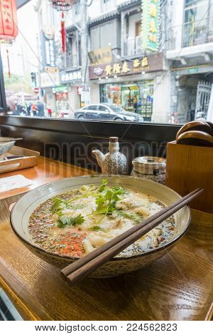 Shanghai, China - Nov 13, 2017: Enjoying Yellow croaker noodle soup, also known as Huangyu Mian, in a restaurant in Nanjing Road Shopping Street in Shanghai.