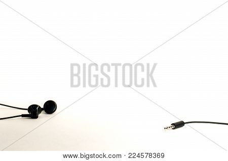 little black earbuds in different positions lying on a white background