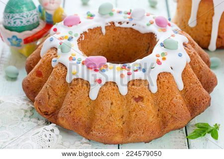 Beautiful Easter food composition - traditional Easter bread kulich paska decorated with white frosting, colorful sugar sprinkling and candy mini eggs