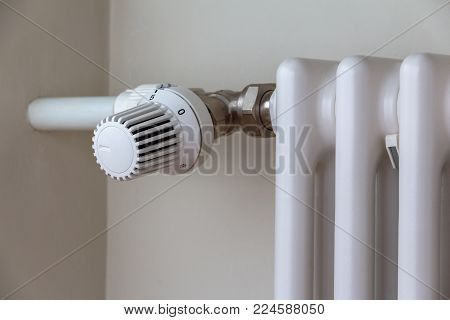 heating temperature controller on white radiator in the apartment