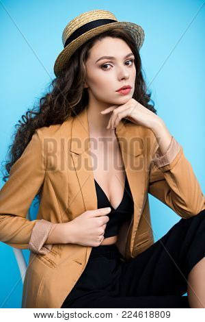 attractive young woman in canotier hat and stylish jacket looking at camera