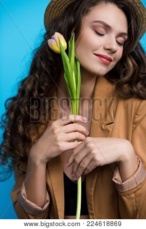 beautiful young woman in canotier hat and jacket holding tulip flower