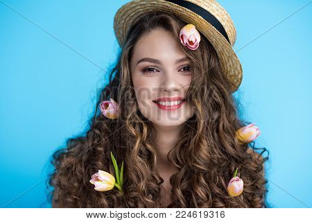 happy young woman in canotier hat with flowers in her long curly hair