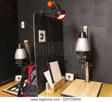 A dark room is set up with old fashion black and white enlargers ready to print pictures.