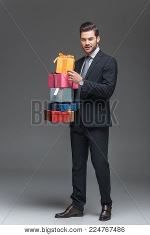 handsome beardman holding gift boxes, isolated on grey