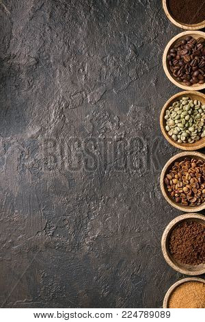 Variety of grounded, instant coffee, different coffee beans, brown sugar in wooden bowls in row over dark texture background. Top view, space