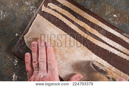 Man cuts dough for noodles from above horizontal