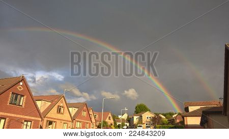A double rainbow showing over above a street.