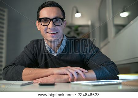 My goal. Optimistic glad male programmer putting hands on the table while gazing at the camera and smiling