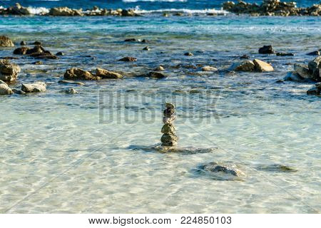 Small pebbles stacked on the sea shore in the Caribbean beach of Baby Beach, Aruba