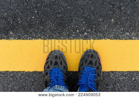 A man standing on asphalt ground with yellow line on the road.