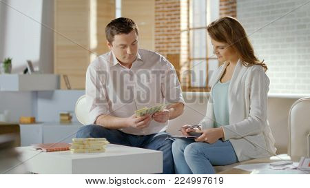 Successful married couple counting cash at home, family budget money, savings HD