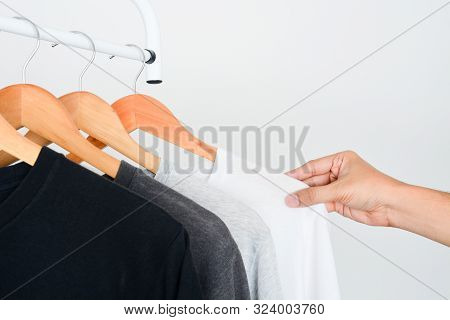 Man's Hand Choosing White Color T-shirt From Collection Of Black, Gray And White Color T-shirt Hangi