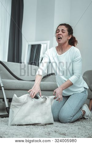 Young Wife Sneezing While Cleaning Her Vacuum Cleaner At Home