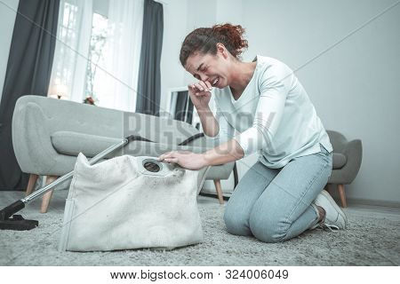Housewife Sitting On Floor And Sneezing Having Allergy To Dust