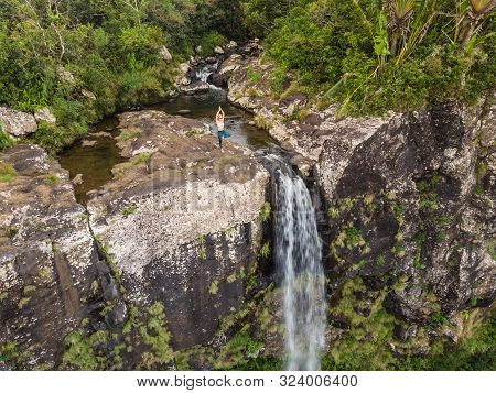Active Sporty Woman Relaxing In Nature, Practicing Yoga On High Clif By 500 Feet Waterfall At Black 